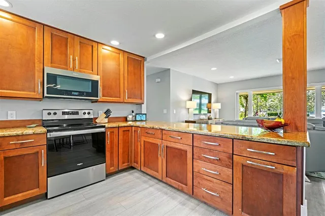 a kitchen with granite countertop wooden cabinets stainless steel appliances and a large window