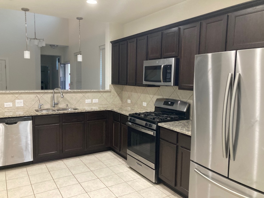 12410 Maypole Bend, Unit 1401 Austin, TX 78717 - Photo 12 of 32 a kitchen with granite countertop wooden cabinets and stainless steel appliances