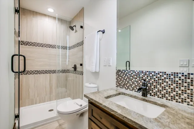 a bathroom with a granite countertop sink toilet and shower
