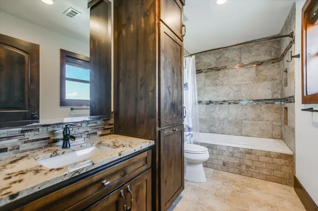 a bathroom with a granite countertop sink a toilet a mirror and shower