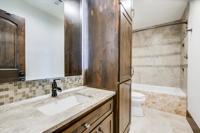 a bathroom with a granite countertop sink a toilet and shower