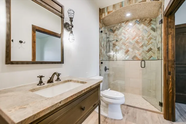 a bathroom with a granite countertop sink toilet a mirror and shower