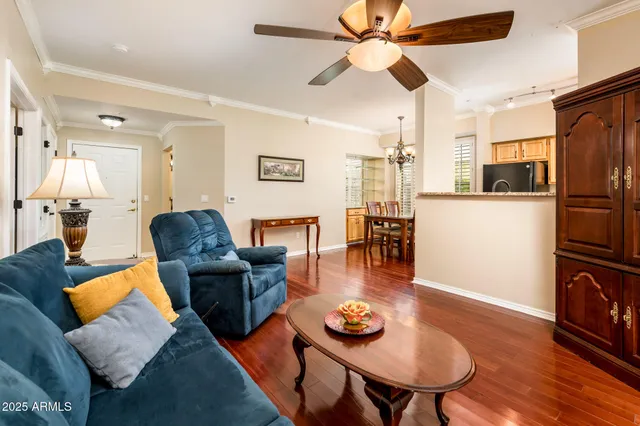 a living room with furniture kitchen view and a wooden floor