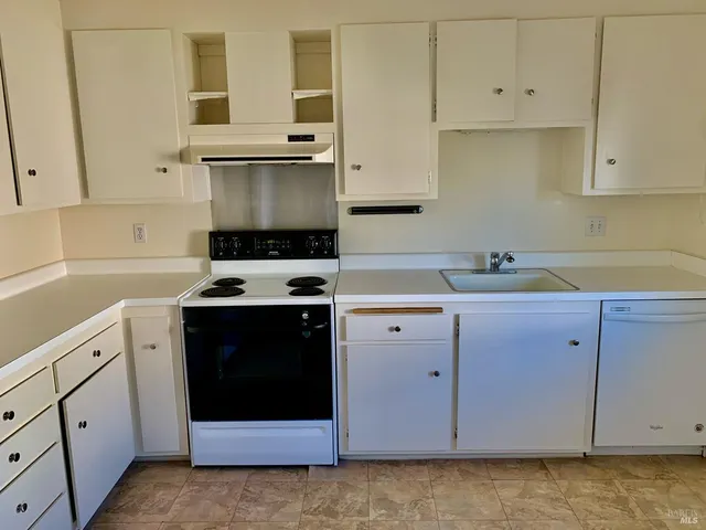 a kitchen with granite countertop white cabinets sink and stainless steel appliances