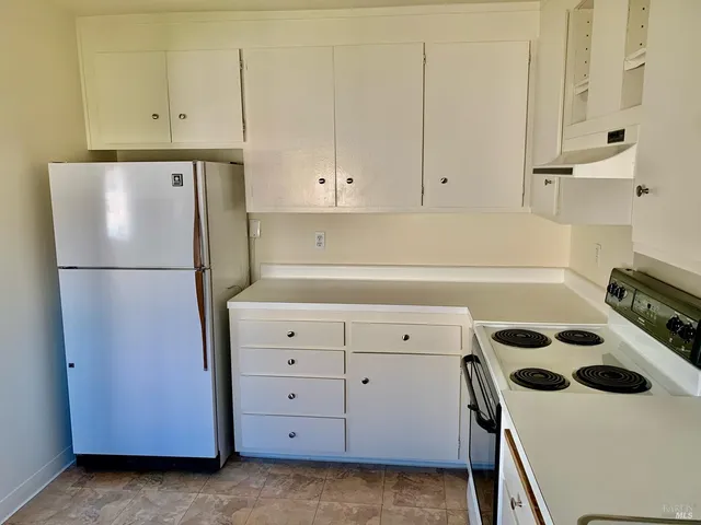 a kitchen with a refrigerator and white cabinets