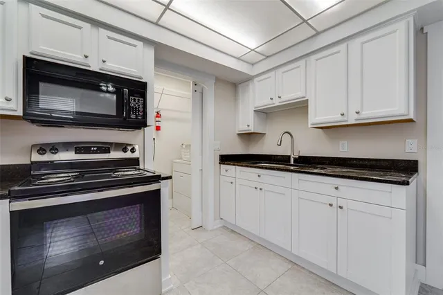 a kitchen with granite countertop a refrigerator and a stove top oven