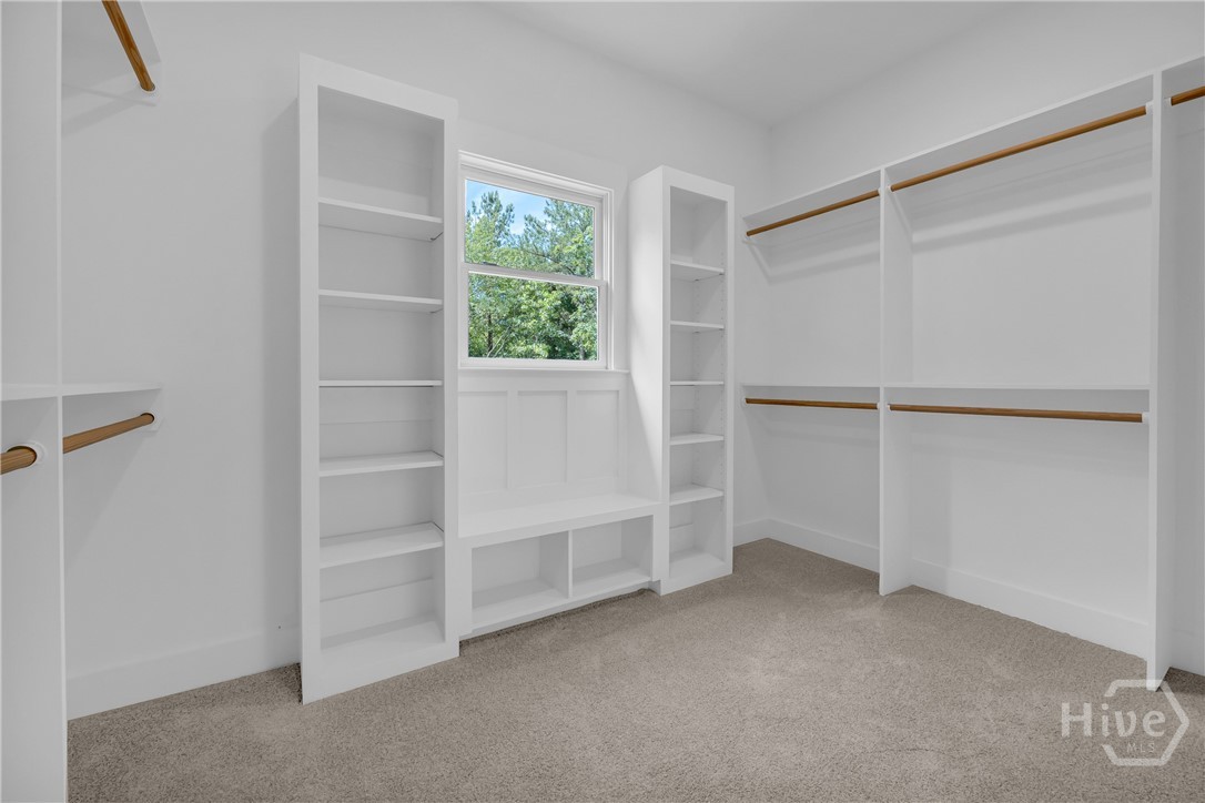 2476 St Martin Way Monroe, GA 30656 - Photo 50 of 75 Walk-in closet featuring built-in shelving, hanging rods, an integrated window bench, and light gray carpet