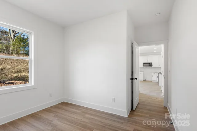 a view of a hallway with wooden floor and a room
