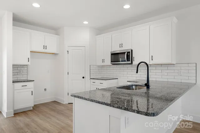a kitchen with granite countertop a sink a stove and cabinets