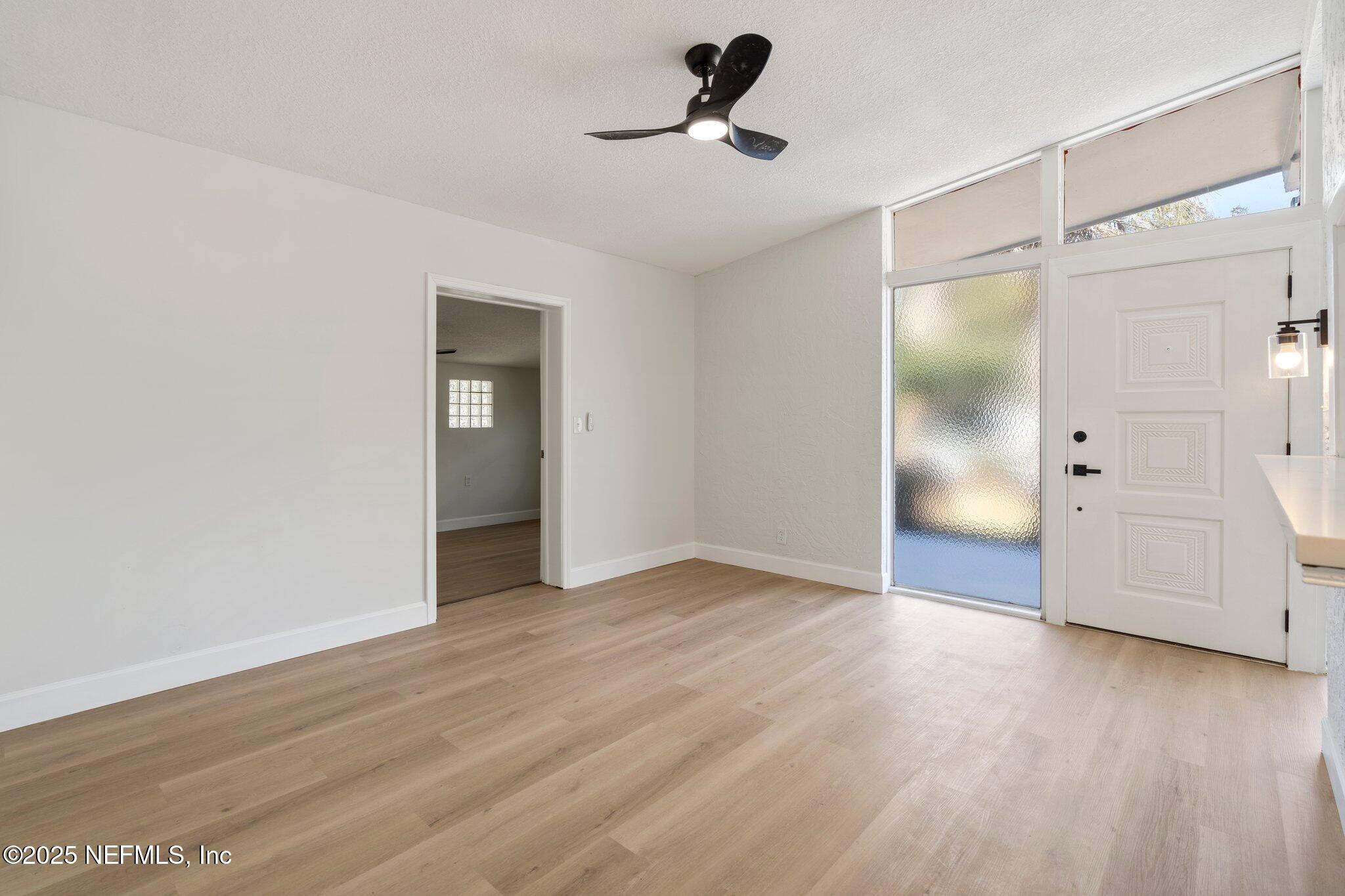 7420 Sandhurst Road South Jacksonville, FL 32277 - Photo 4 of 35 a view of an empty room with wooden floor and a ceiling fan
