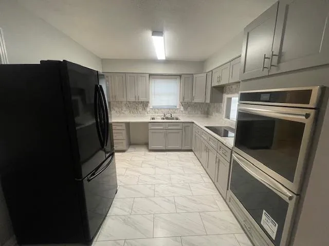 a kitchen with stainless steel appliances granite countertop a refrigerator and a stove top oven