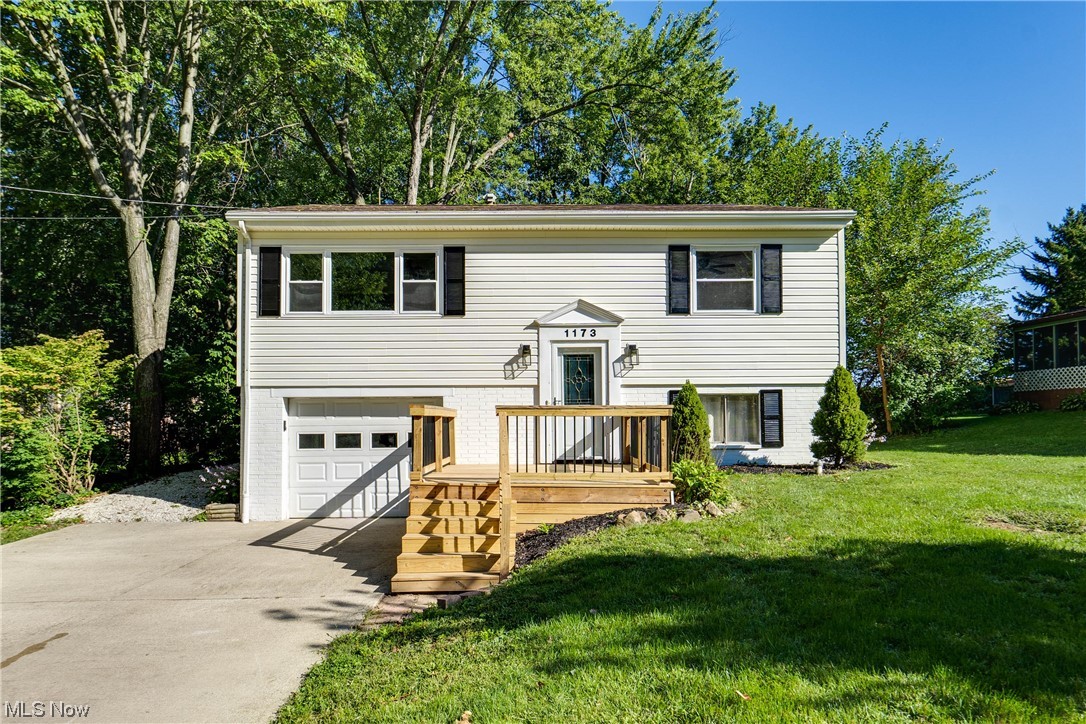 Raised ranch featuring garage, a deck, and a front yard