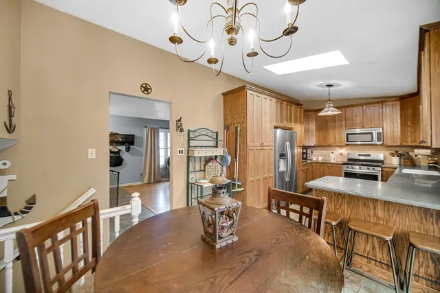 a kitchen with stainless steel appliances granite countertop a refrigerator a stove top oven a sink dishwasher and couches with wooden floor