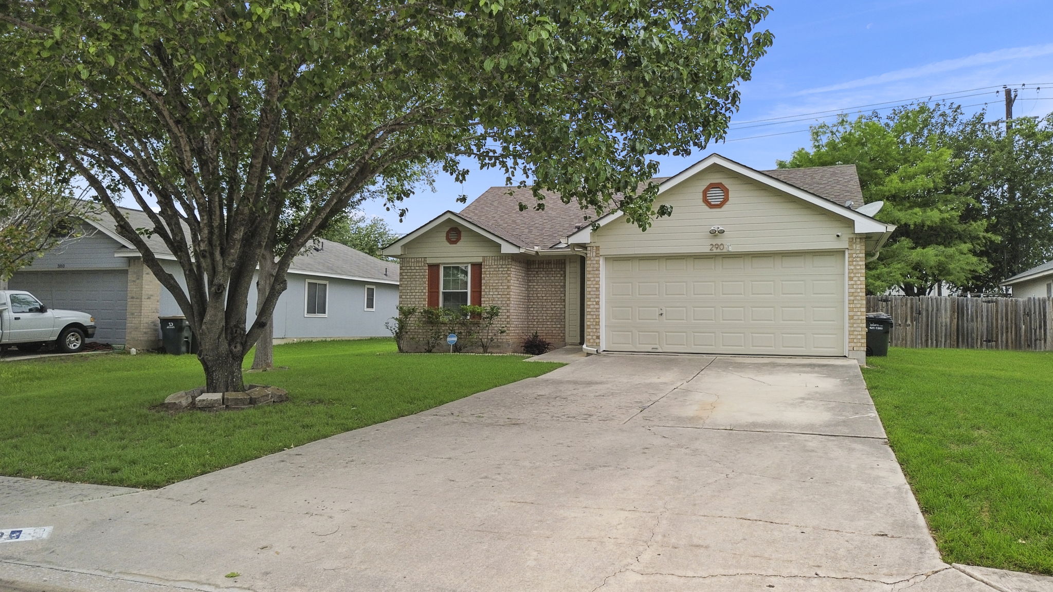 290 Bailey Loop Kyle, TX 78640 - Photo 6 of 33 Brick and siding exterior featuring a two-car garage, concrete driveway, and a mature front yard tree