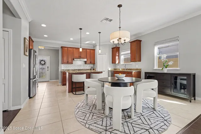 a dining room with stainless steel appliances kitchen island granite countertop a dining table chairs and a refrigerator