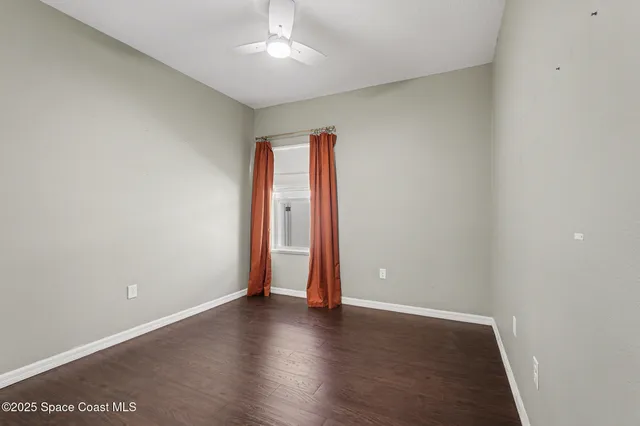 an empty room with wooden floor and ceiling fan