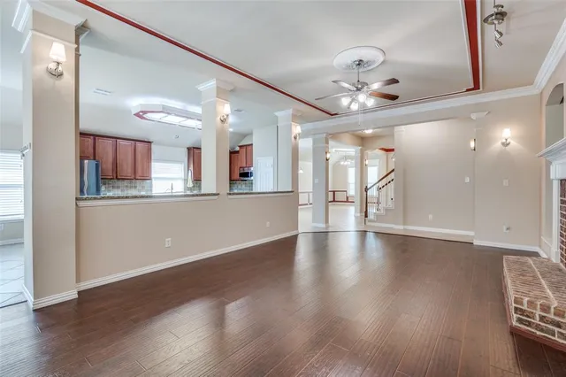 a view of an empty room with kitchen and window