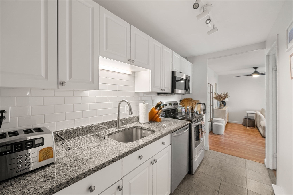 94 Beacon Street, Unit 83 Somerville, MA 02143 - Photo 11 of 22 a kitchen with stainless steel appliances granite countertop a sink stove and cabinets