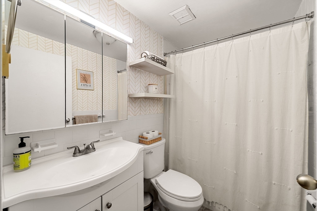 94 Beacon Street, Unit 83 Somerville, MA 02143 - Photo 13 of 22 a bathroom with a sink a toilet and shower curtain