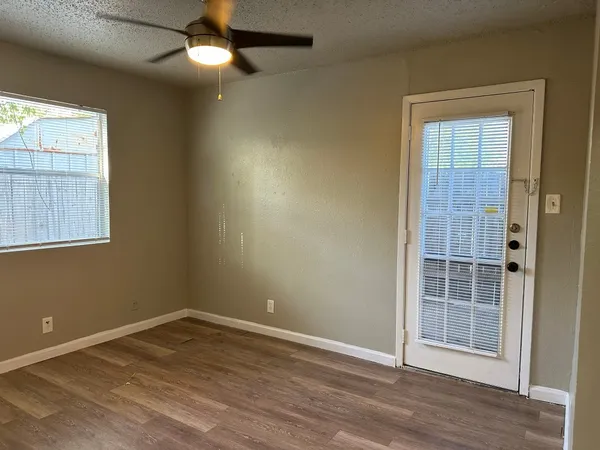 an empty room with a window and a chandelier fan