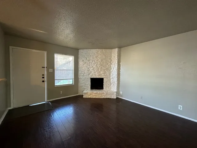 an empty room with wooden floor and a fireplace