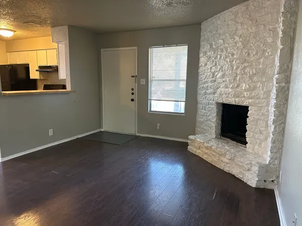 a view of an empty room with wooden floor and a fireplace