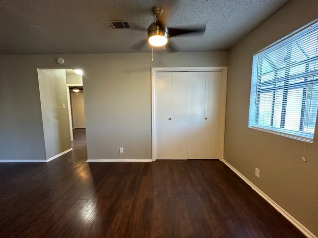 a view of an empty room with wooden floor and a window