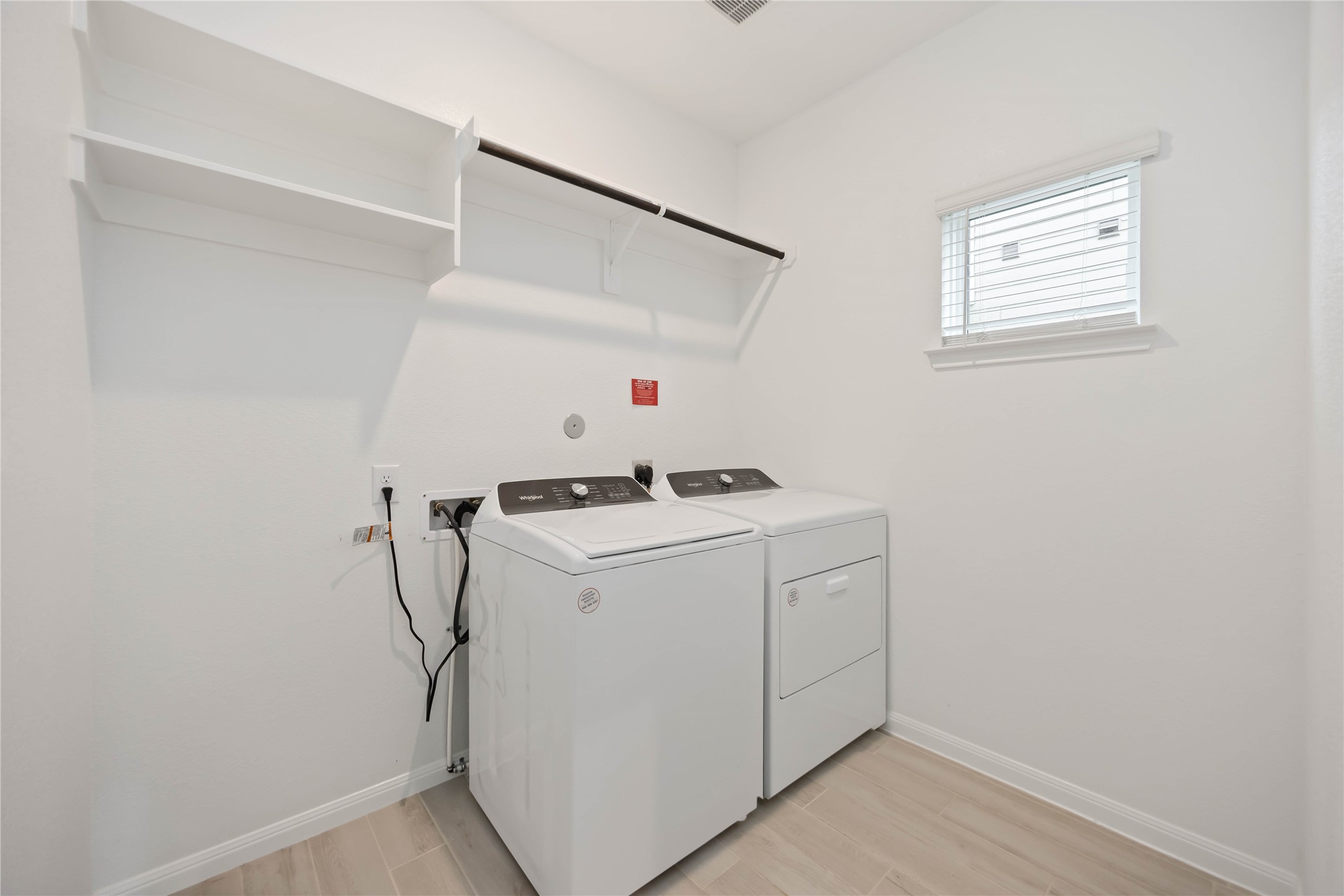 6814 Ventura Drive Rosharon, TX 77583 - Photo 11 of 30 The laundry room is spacious and thoughtfully designed, with a window for natural light and overhead built-in shelving that keeps everything within easy reach.