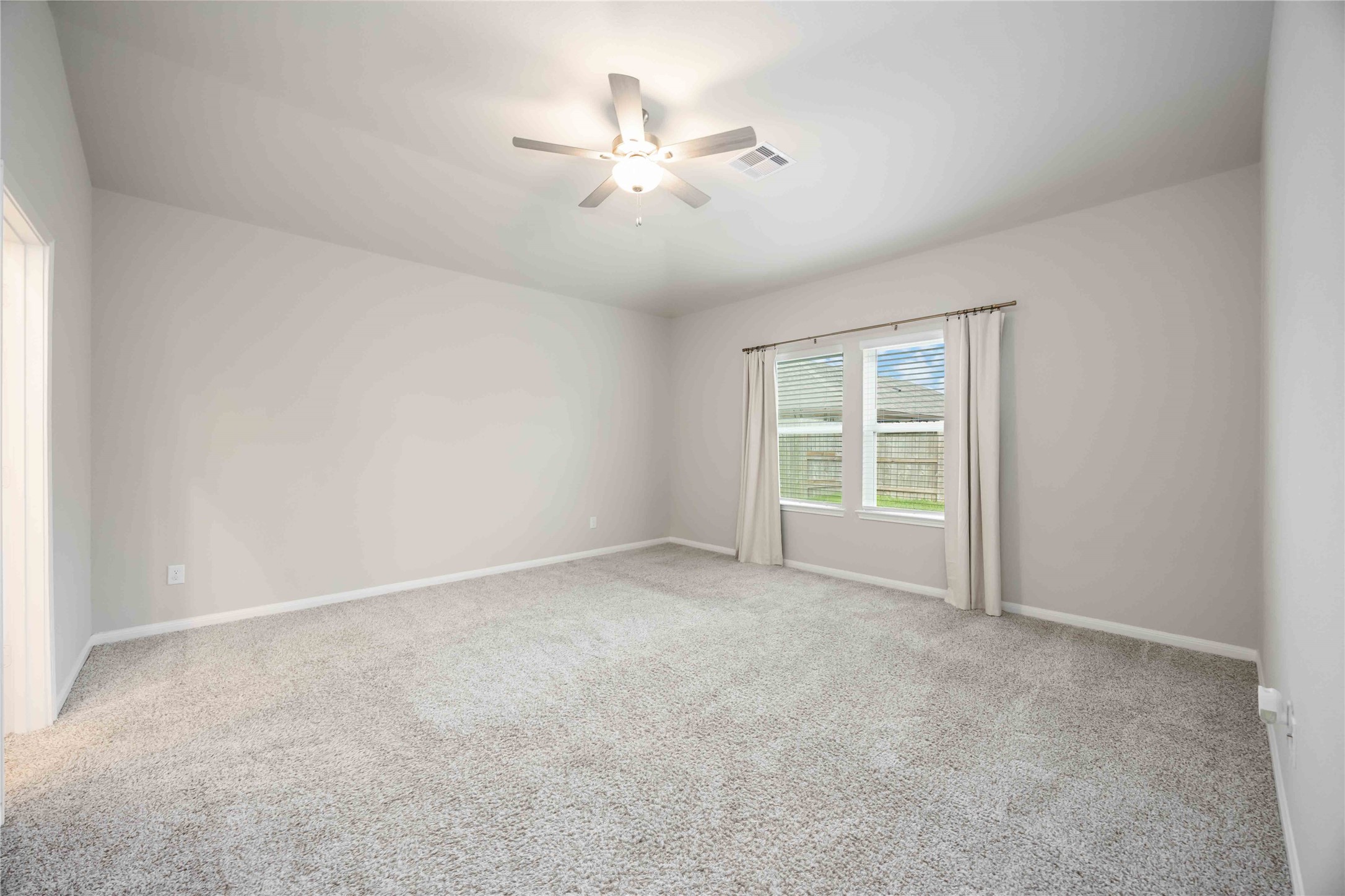 6814 Ventura Drive Rosharon, TX 77583 - Photo 12 of 30 The primary suite is peaceful and private, with soft carpeting underfoot, broad windows filtering sunlight, and a ceiling fan for a gentle breeze—a quiet retreat to truly unwind.