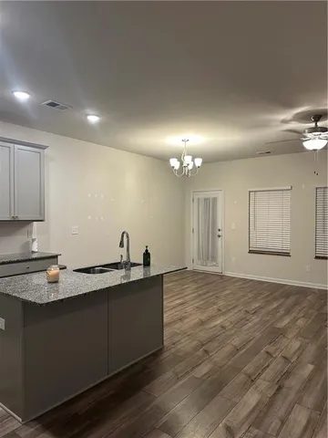 a empty room with kitchen island a sink wooden floor and glass door
