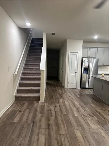 a view of an empty room with wooden floor and stairs