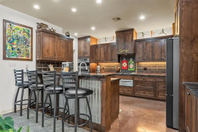 a kitchen with kitchen island granite countertop wooden cabinets and stainless steel appliances