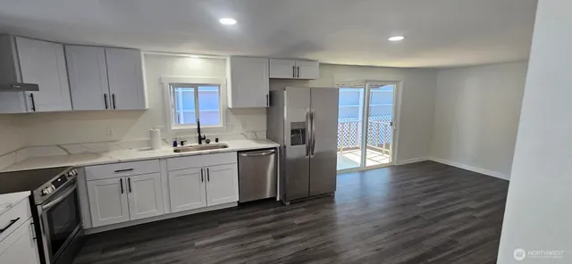 a kitchen with stainless steel appliances granite countertop a refrigerator a sink dishwasher and a stove with wooden floor