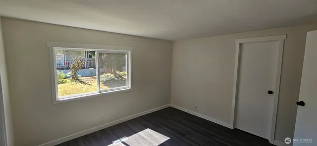 a view of an empty room with wooden floor and a window