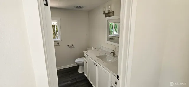 a bathroom with a granite countertop toilet and a sink