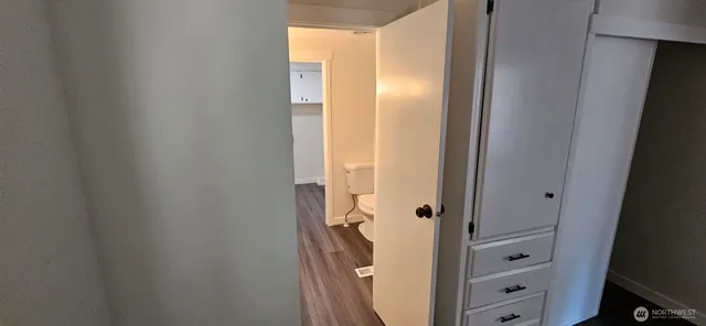 a view of hallway with window and wooden floor