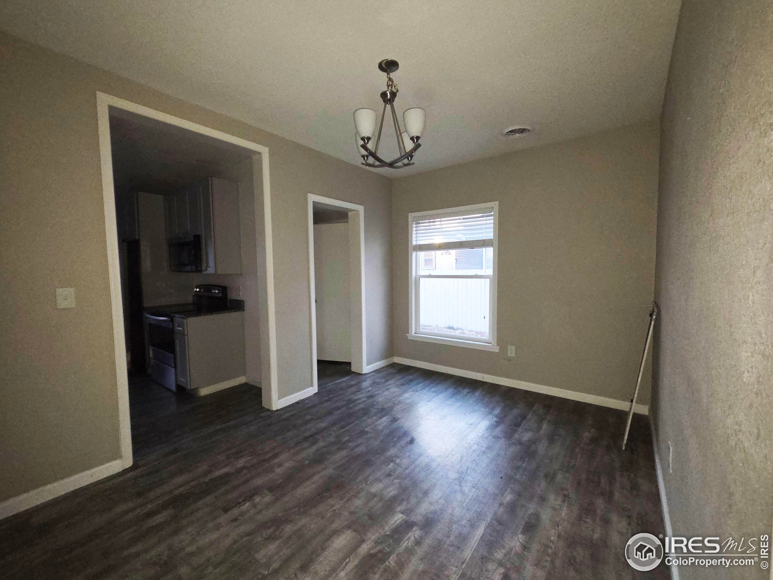 523 Chestnut Street Sterling, CO 80751 - Photo 3 of 13 wooden floor in an empty room with a window