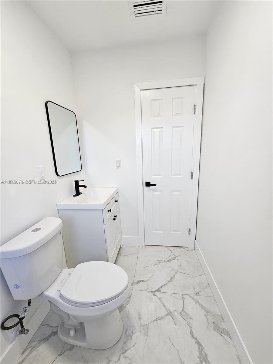 1117 West 26th Court Riviera Beach, FL 33404 - Photo 16 of 16 a white toilet sitting next to a bathroom sink