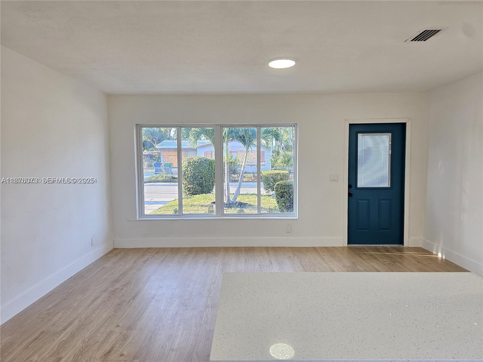 1117 West 26th Court Riviera Beach, FL 33404 - Photo 3 of 16 a view of an empty room with wooden floor and a window