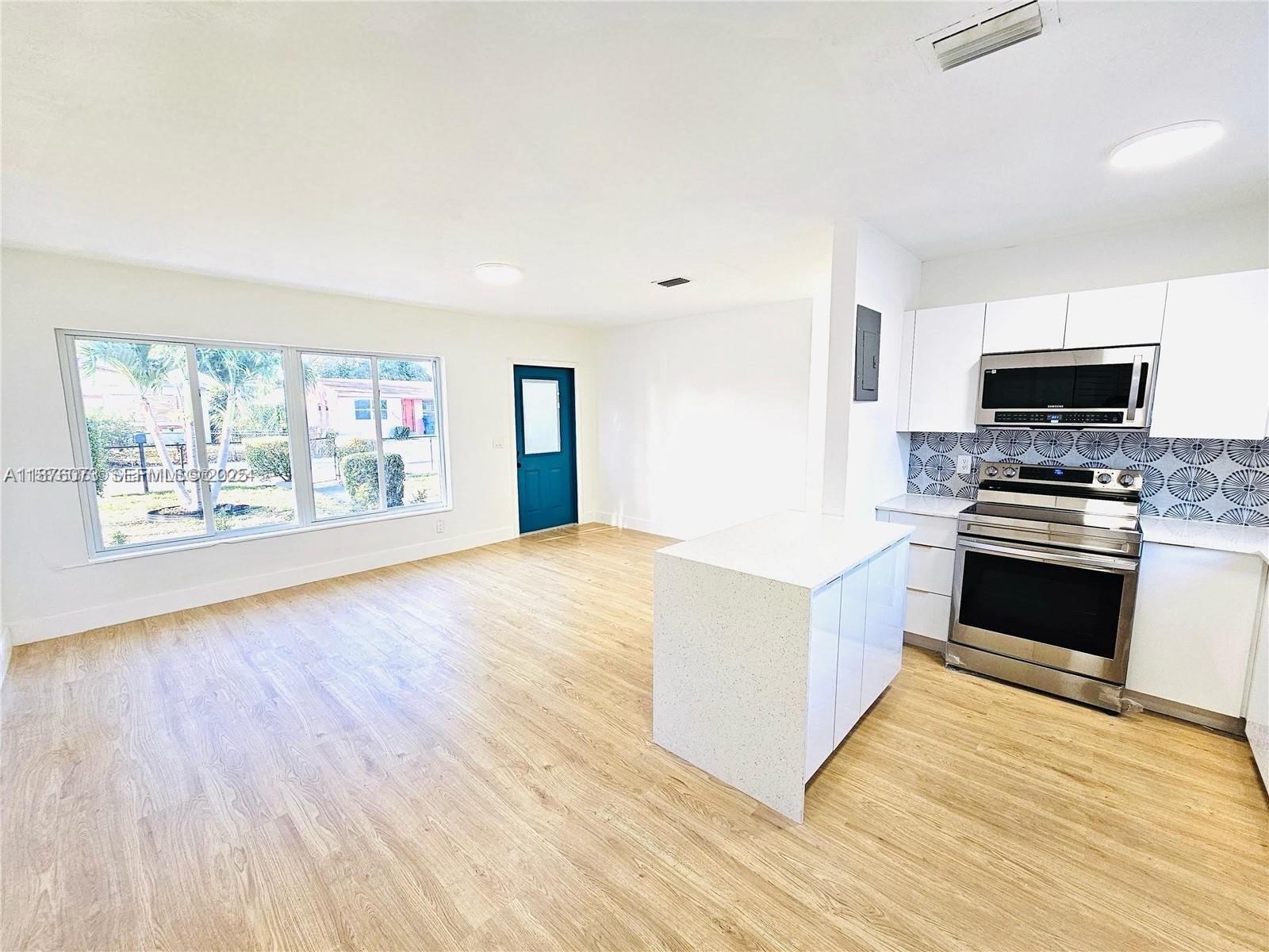 1117 West 26th Court Riviera Beach, FL 33404 - Photo 5 of 16 a kitchen with stainless steel appliances a stove top oven a sink and a microwave