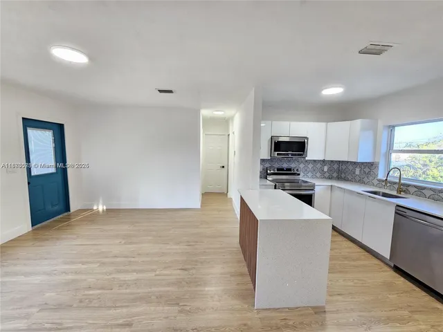 a large kitchen with cabinets and wooden floor