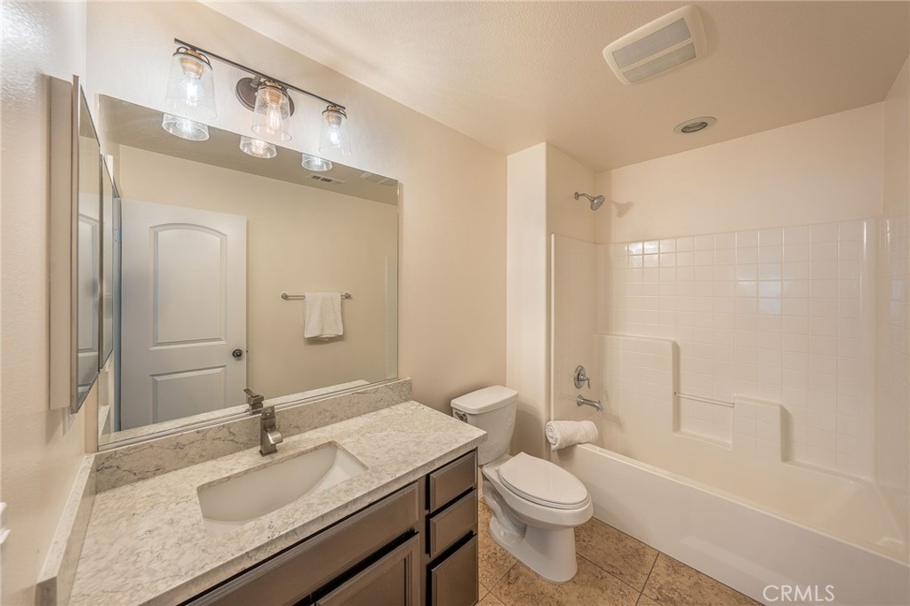 5062 Woodley Ridge Drive Rancho Cucamonga, CA 91739 - Photo 22 of 33 a bathroom with a granite countertop sink toilet a large mirror a bathtub and shower