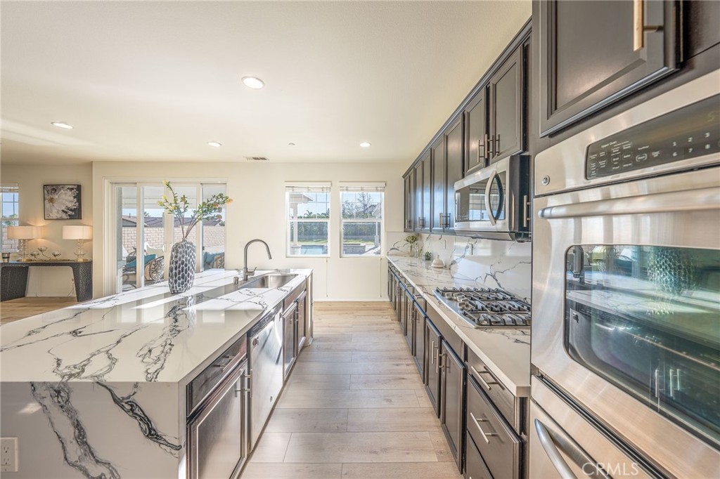 5062 Woodley Ridge Drive Rancho Cucamonga, CA 91739 - Photo 9 of 33 a large kitchen with stainless steel appliances granite countertop a lot of counter space and a sink
