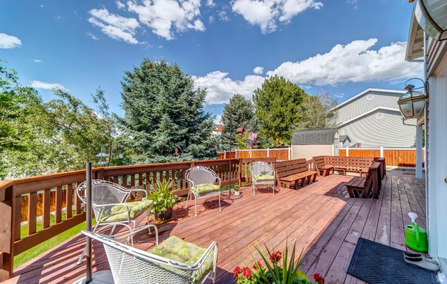 1273 Grayson Court Sandy, UT 84094 - Photo 24 of 27 Expansive wood-finish deck with integrated bench seating, wood-slat railing, and a permanent exterior light fixture