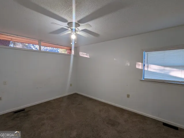 an empty room with a fan & a window