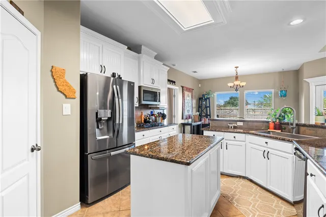 a kitchen with stainless steel appliances granite countertop a refrigerator a sink a stove a dining table and chairs