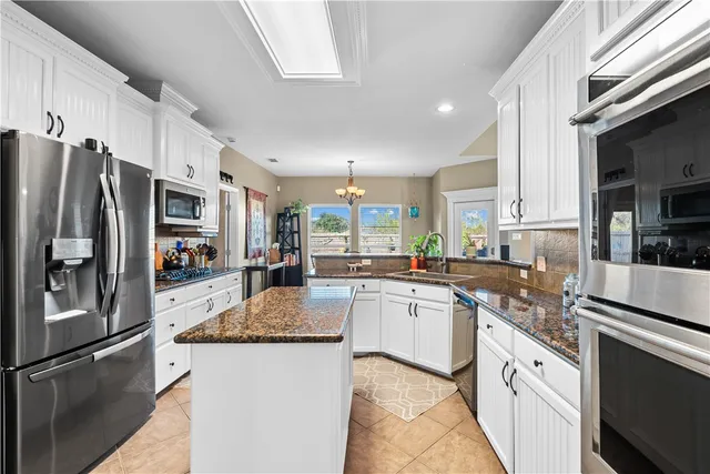 a large kitchen with granite countertop a large counter top stainless steel appliances and cabinets
