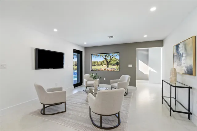 a living room with furniture a flat screen tv and a large window