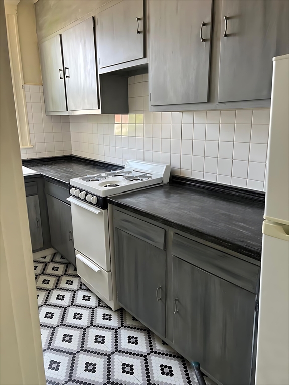 71 Harwood Street, Unit 12 Lynn, MA 01902 - Photo 3 of 5 a kitchen with granite countertop a stove a sink and a microwave