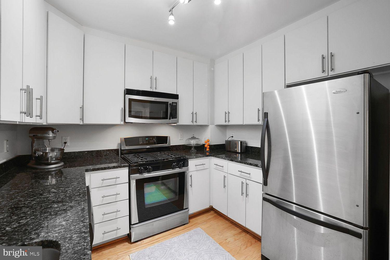 915 E Street Northwest, Unit 403 Washington, DC 20004 - Photo 11 of 30 a kitchen with white cabinets and stainless steel appliances
